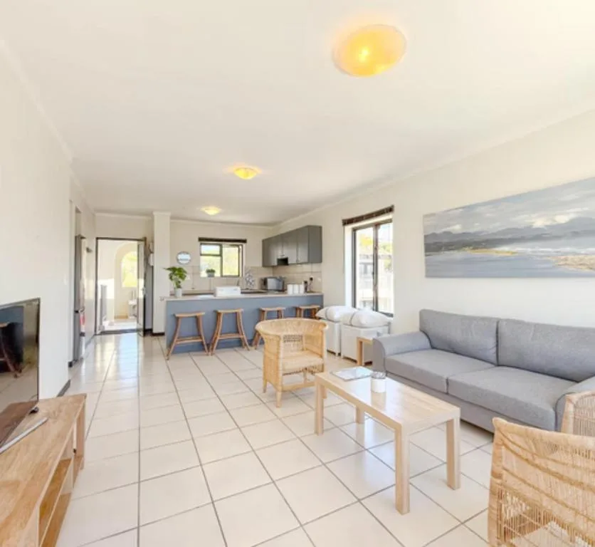 Open-plan lounge with gray sofa, wooden furniture, and kitchen view