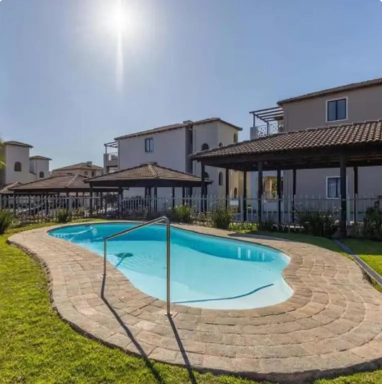 Sparkling blue swimming pool with safety fencing surrounded by manicured grounds
