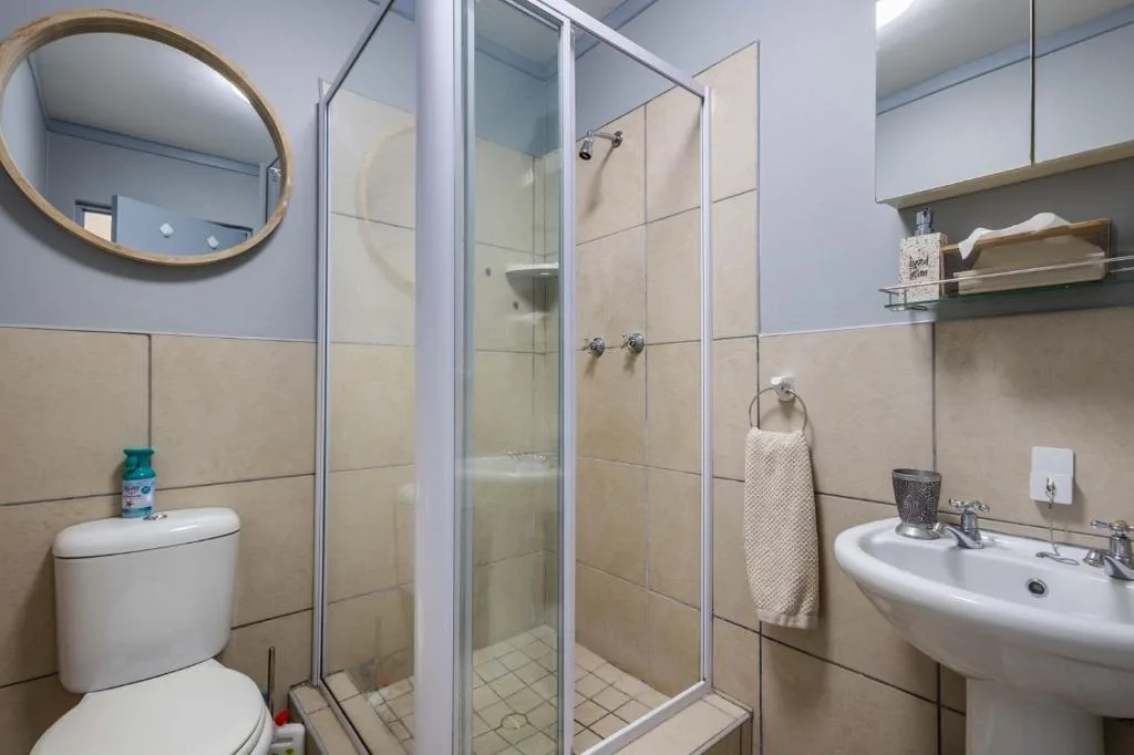 Modern bathroom with shower enclosure, vanity sink, and round mirror