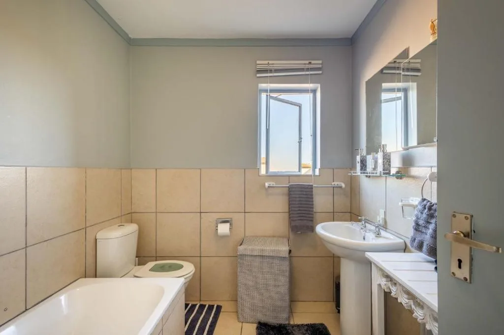 Bright bathroom with bathtub, toilet, sink, and large mirror