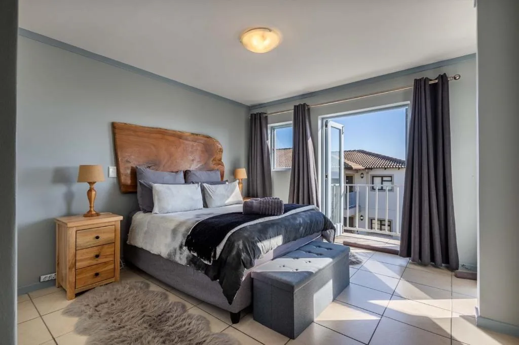 Spacious bedroom with queen bed, wooden nightstand, and ocean views through sliding doors