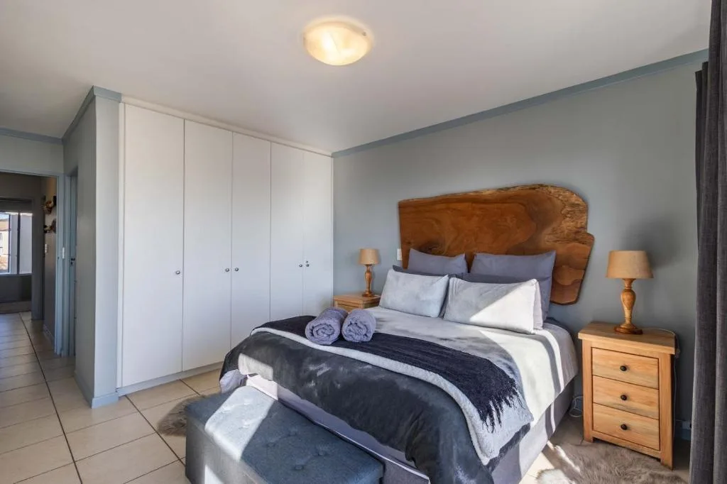 Spacious bedroom with wooden headboard, built-in wardrobes, and bedside tables