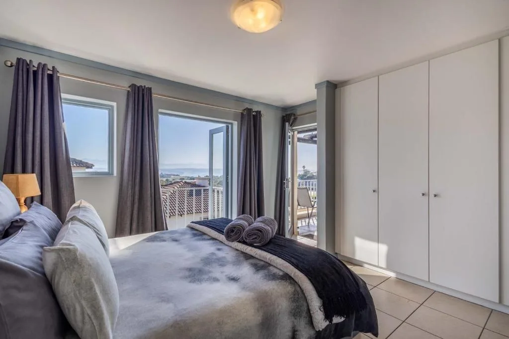 Spacious bedroom with ocean views through multiple windows and doors