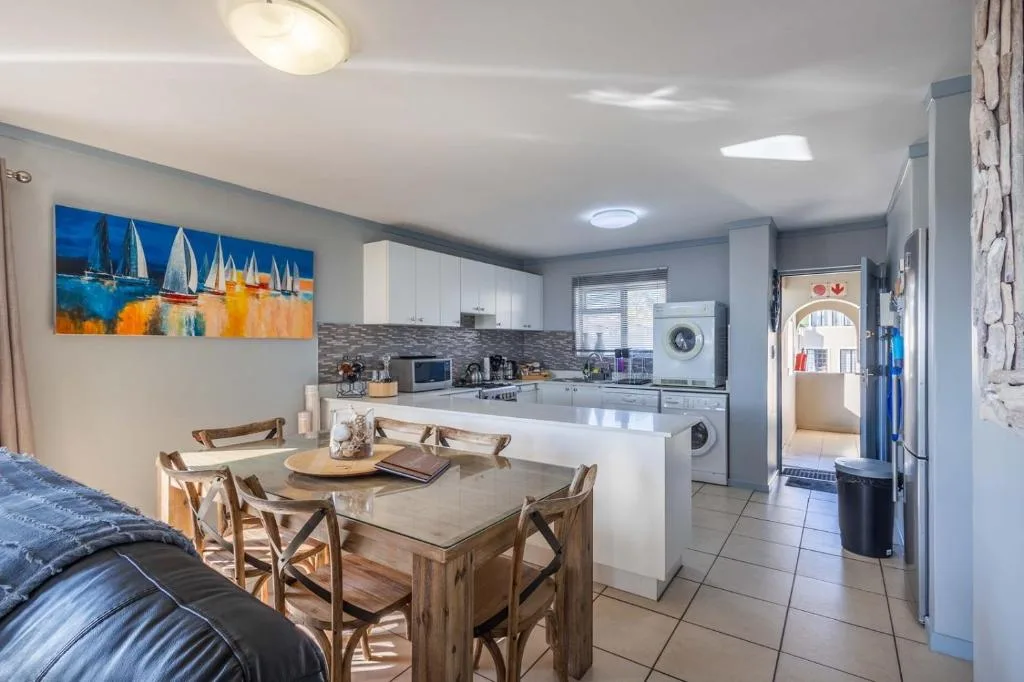 Wooden dining table with four chairs in open-plan kitchen and living area