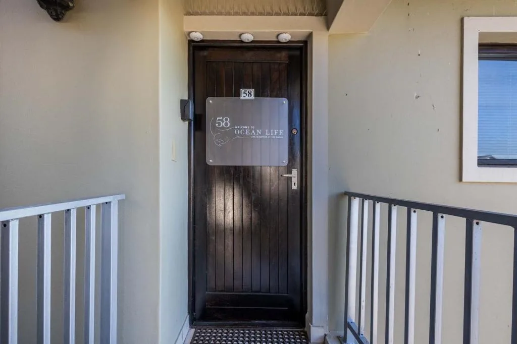 Dark wooden entrance door with Ocean Life signage and unit number fifty-eight