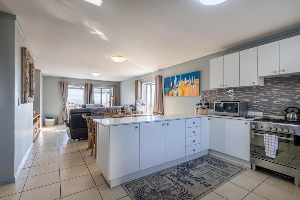 Modern open-plan kitchen with white cabinetry and stainless steel appliances