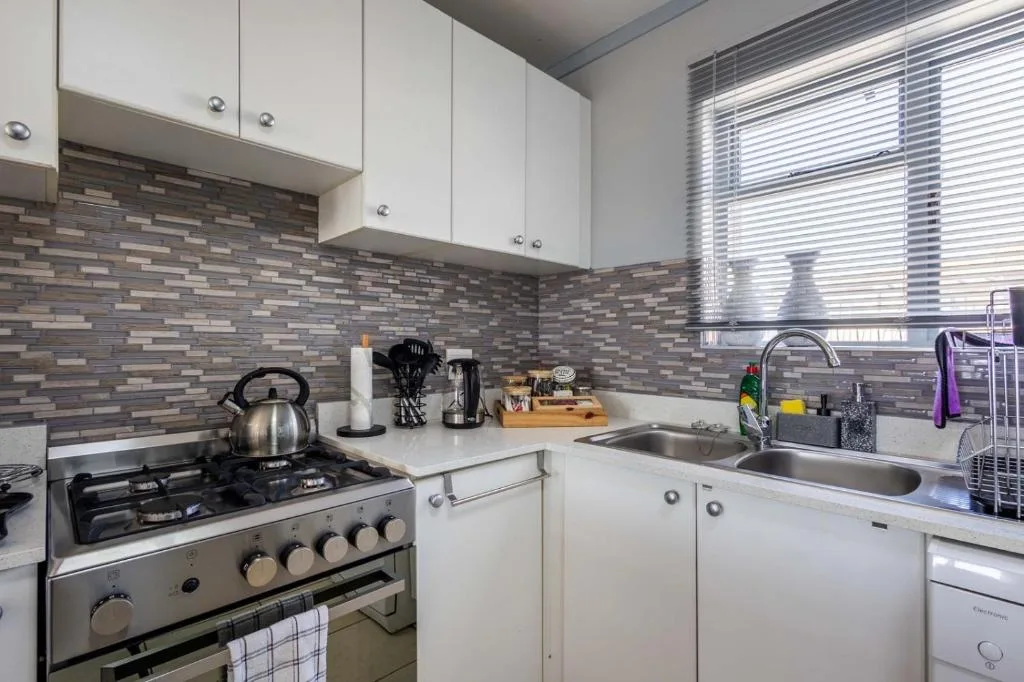 Modern kitchen with white cabinetry, stainless steel gas stove, and tiled backsplash