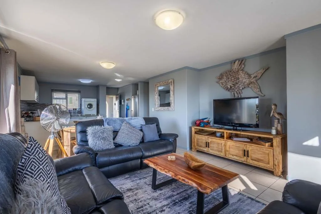 Open-plan lounge with blue leather sofa, TV, wooden furniture and coastal decor