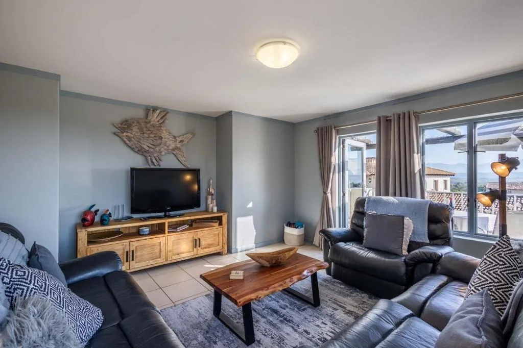 Spacious lounge with black leather seating and wooden TV unit