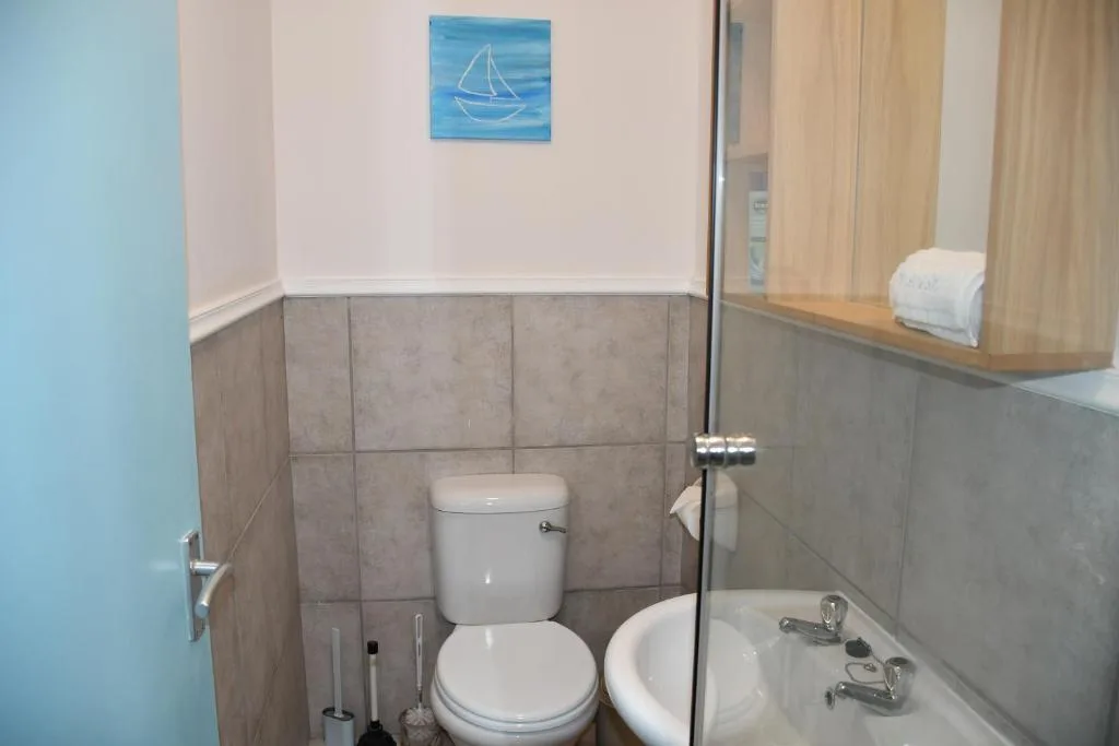Clean bathroom with toilet, sink, tiled walls, and nautical artwork