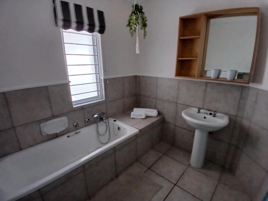 Spacious bathroom with bathtub, pedestal sink, and wall-mounted mirror cabinet