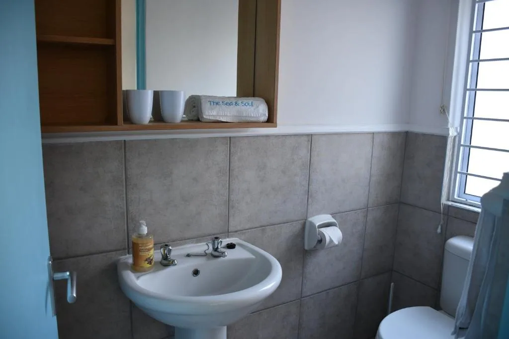 Bathroom vanity with round sink, mirror, and tiled walls in apartment