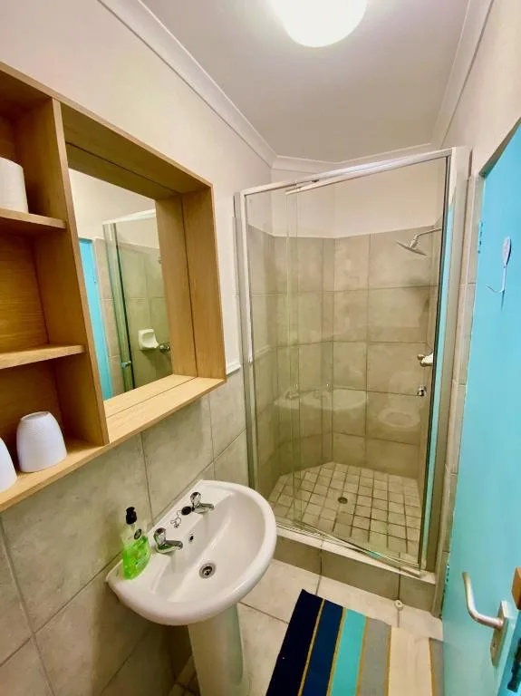 Modern bathroom with glass shower enclosure and wooden vanity mirror