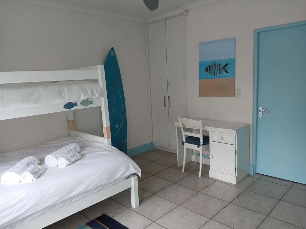 Bright bedroom with white bunk bed, turquoise accents, and coastal decor