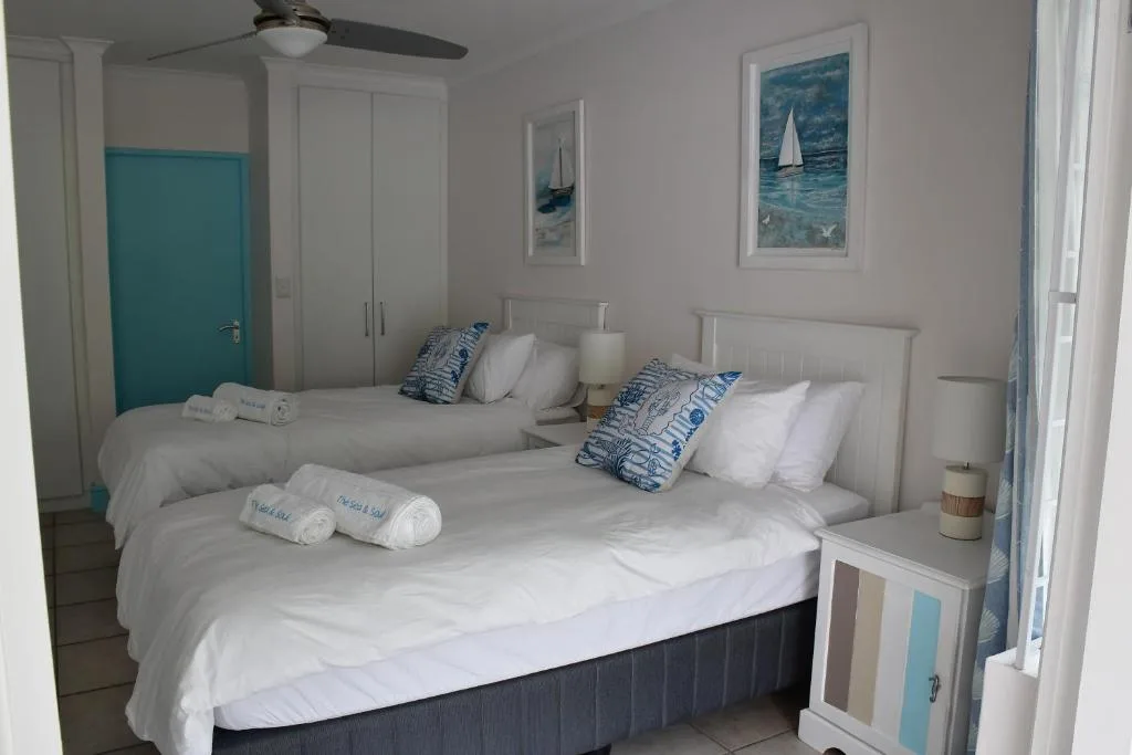 Bright bedroom with two queen beds, nautical decor, and coastal artwork