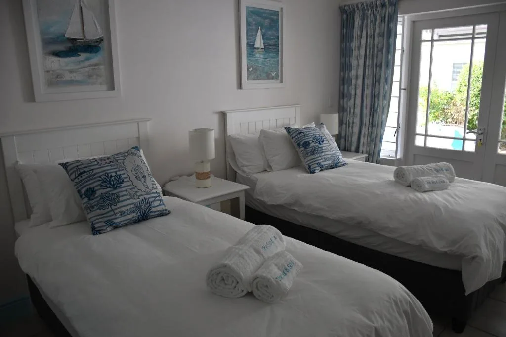 Bright bedroom with twin beds, nautical decor, and glass doors to outdoor patio