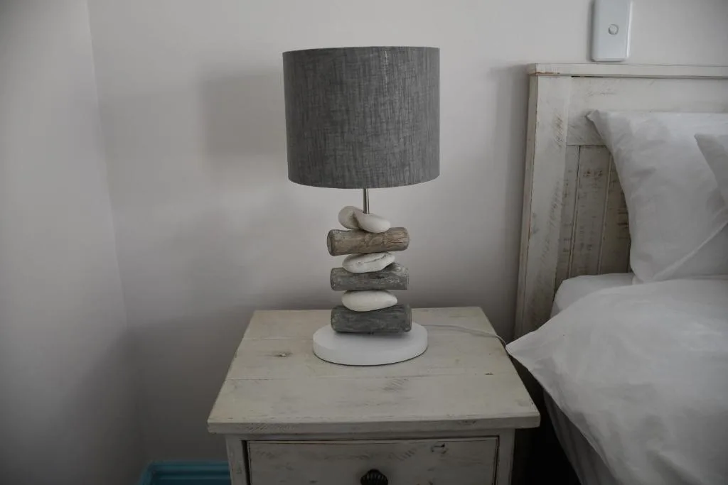 Coastal-style bedside lamp with driftwood base on whitewashed nightstand