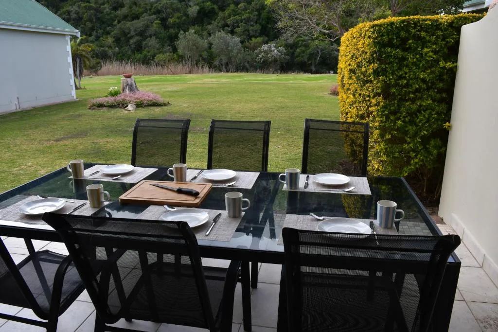 Outdoor dining setup on patio with garden views and yellow hedging