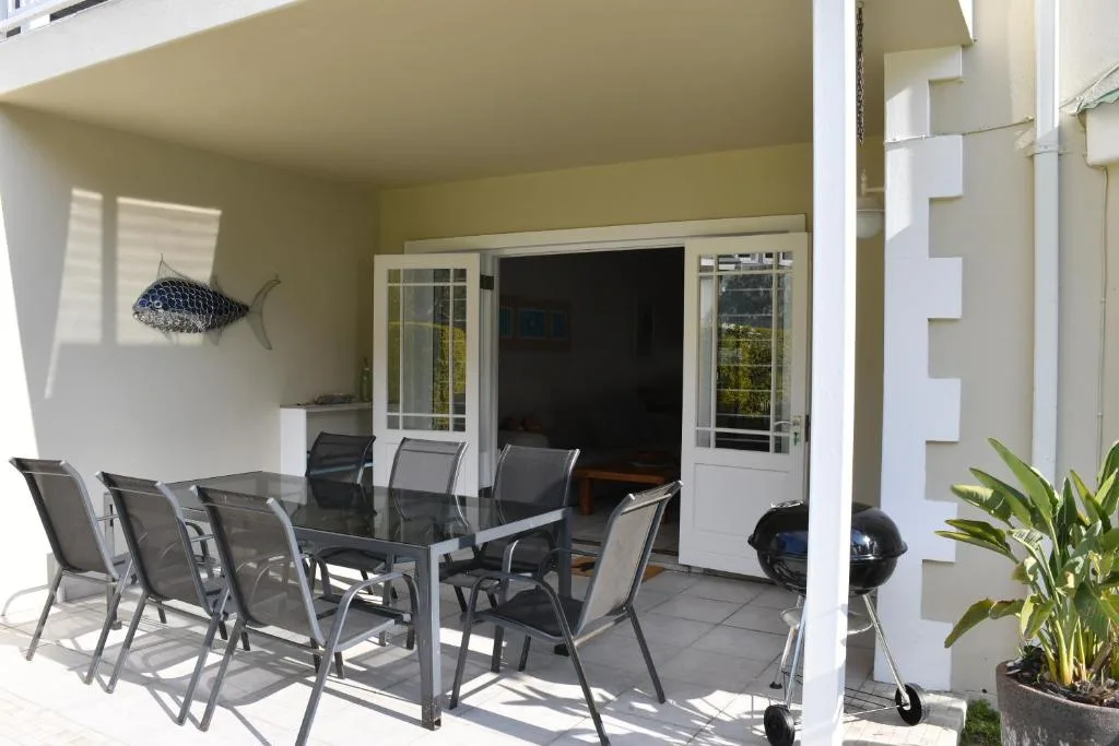 Covered patio with dining table, chairs, and ocean-view doors