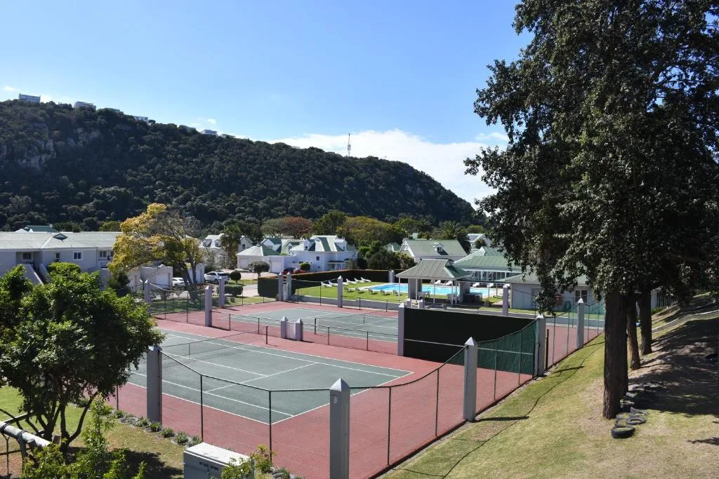 Tennis courts and pool area with mountain backdrop and white buildings