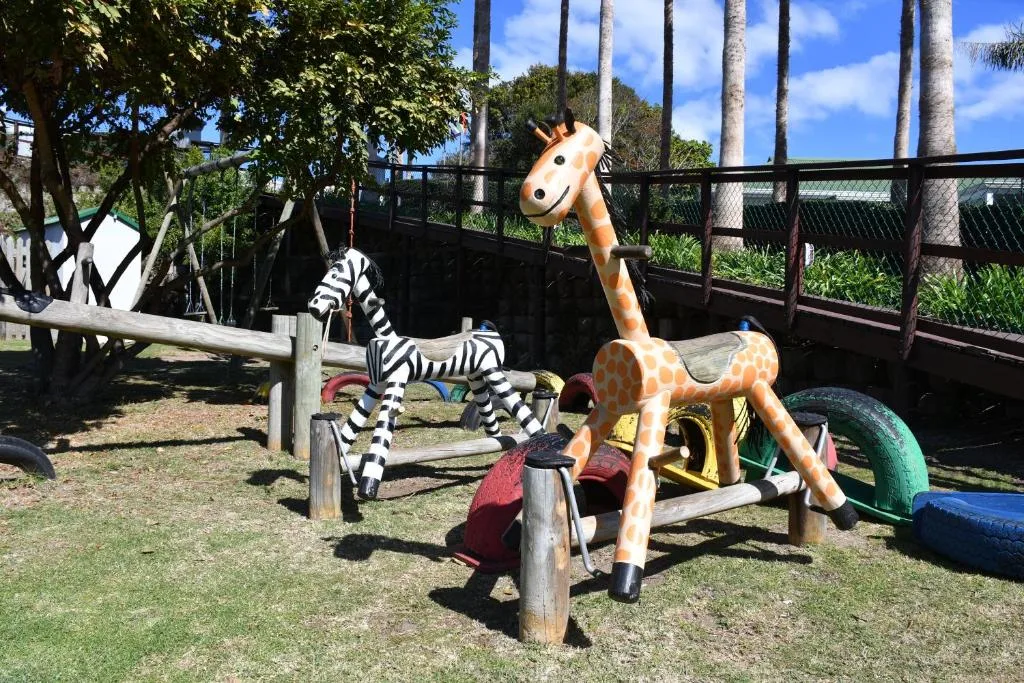 Colorful playground equipment with giraffe and zebra toy sculptures in garden area