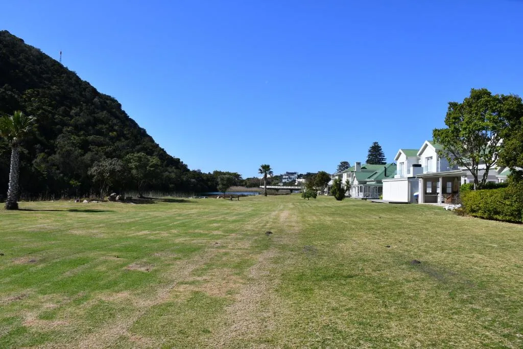 White villa with green roof on sprawling manicured lawn overlooking lagoon