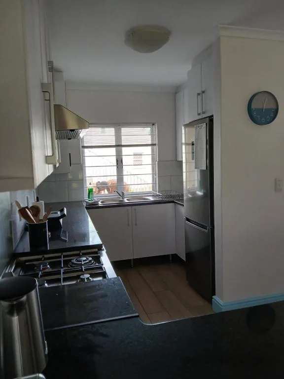 Modern kitchen with gas stove, black countertops, and bright window overlooking town