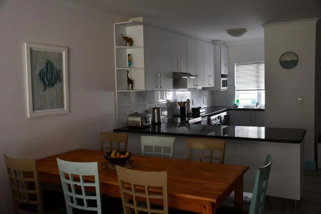 Modern kitchen with black counters, white cabinetry, and dining table seating