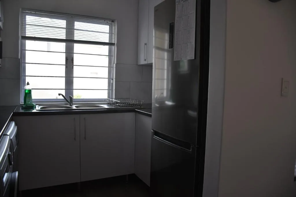 Modern kitchen with black cabinetry, sink, refrigerator, and bright window