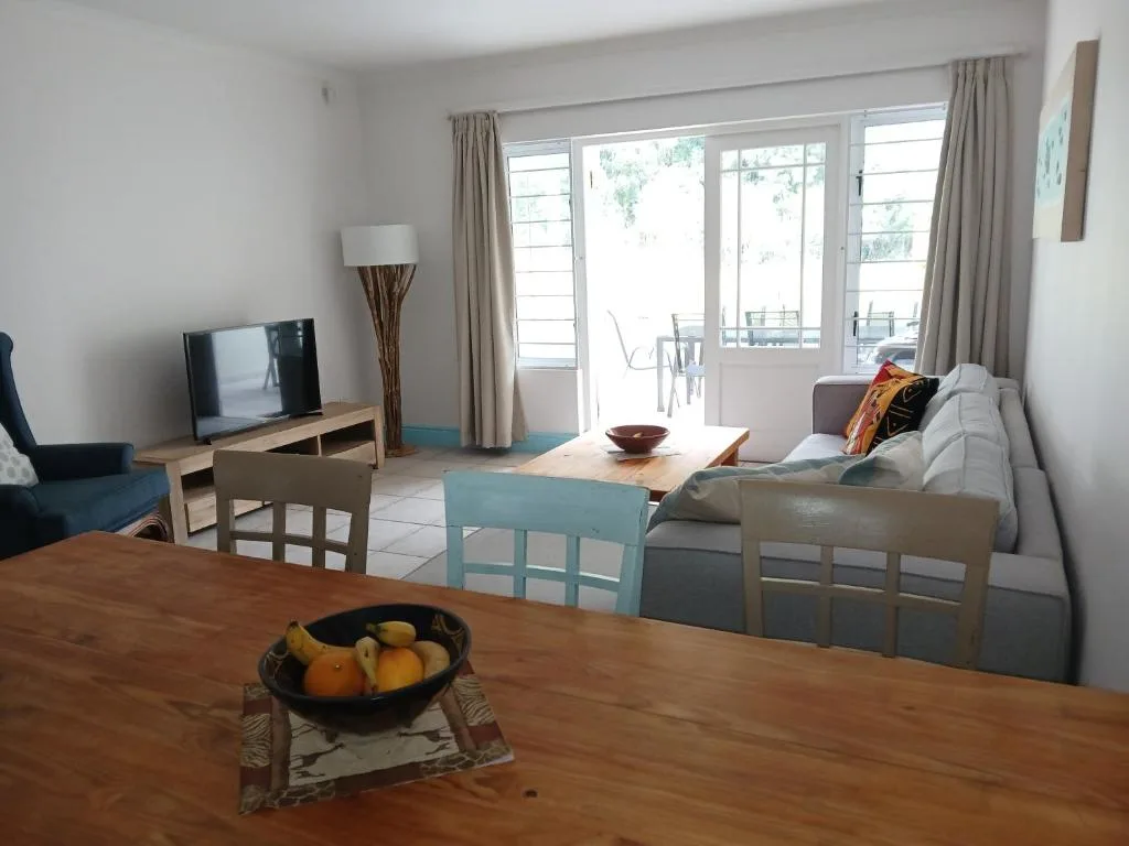 Bright living room with gray sofa, TV, and glass doors opening to balcony