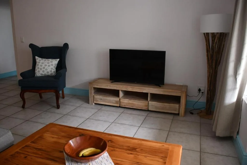 Living room with black wingback chair, wooden TV stand, and tiled floor