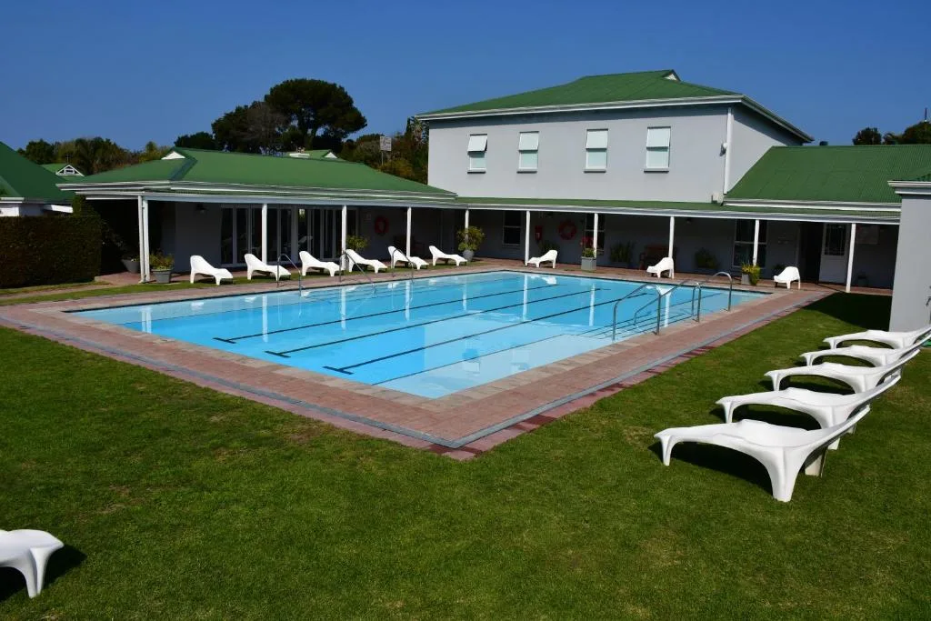 Olympic-sized swimming pool with lane markings and white loungers on manicured lawn