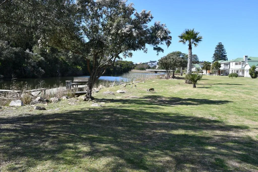 Lagoon view with manicured gardens, palm trees, and white house in background