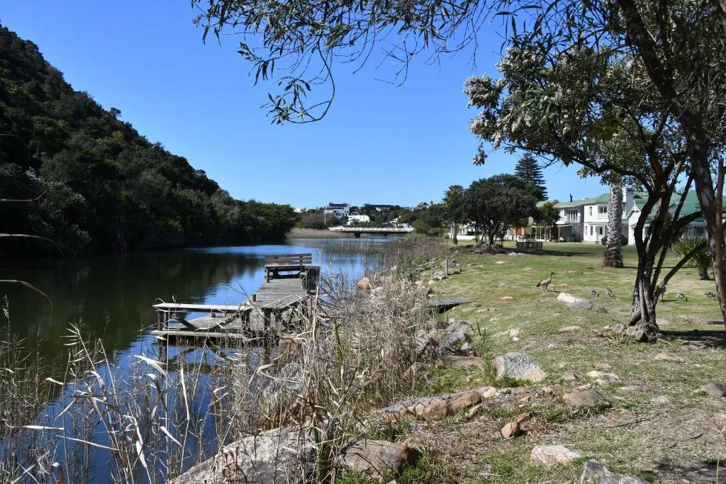 Scenic waterfront view with wooden dock, lagoon, and residential properties beyond