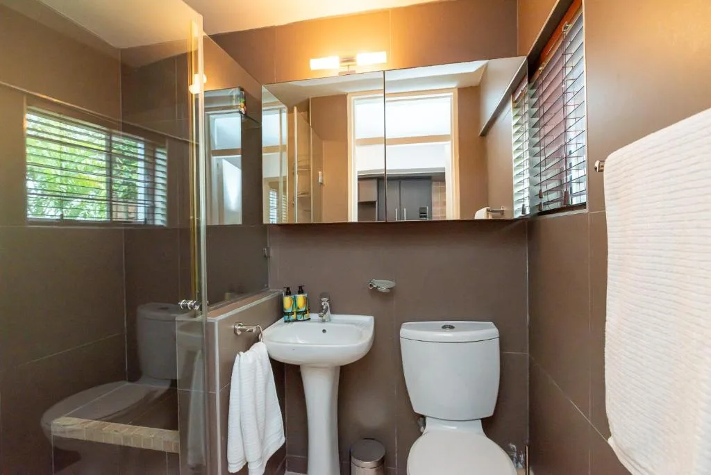Modern bathroom with pedestal sink, toilet, and glass shower enclosure