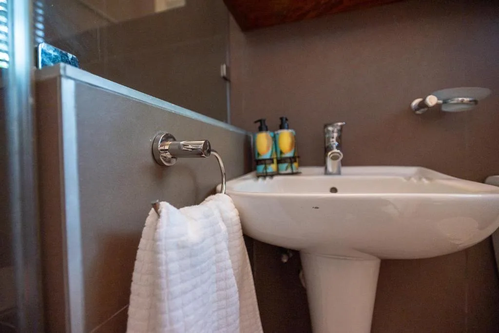 Bathroom vanity with pedestal sink, toiletries, and white towel