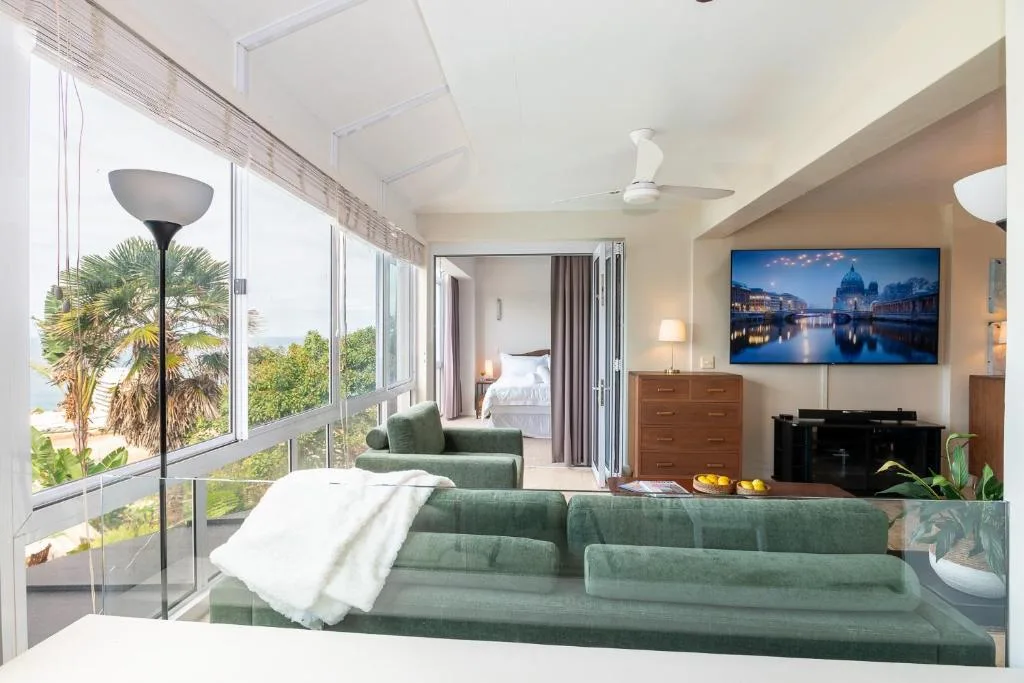 Modern bedroom with green seating area and views of tropical gardens