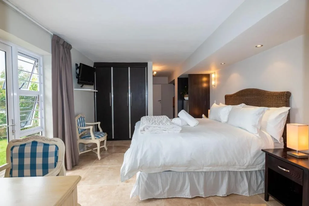 Bright bedroom with double bed, woven headboard, and garden view through windows
