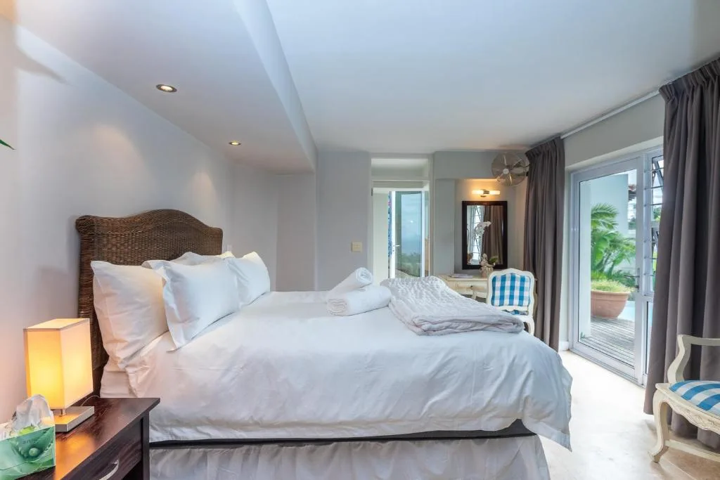 Bright bedroom with woven headboard, white linens, and deck access