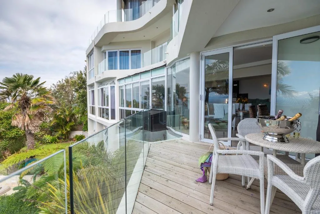 Spacious wooden deck with dining table and modern glass railings overlooking garden