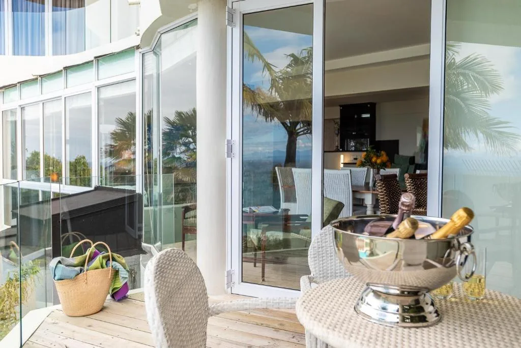 Wooden deck with table, chairs, and ocean views through glass doors