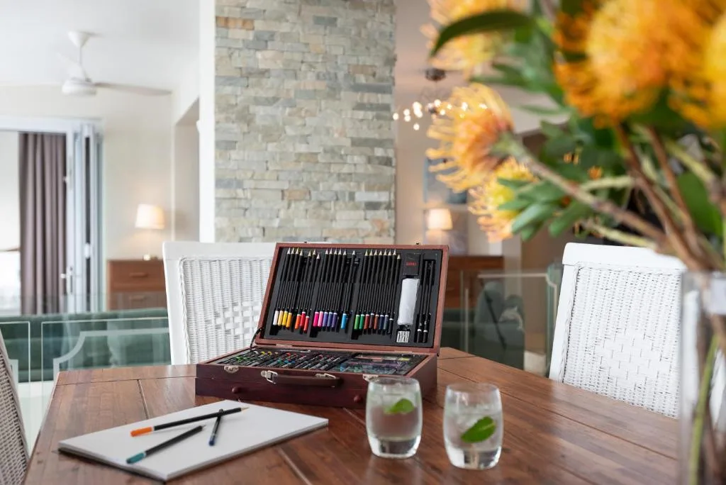 Art supplies and refreshments arranged on wooden dining table with flowers