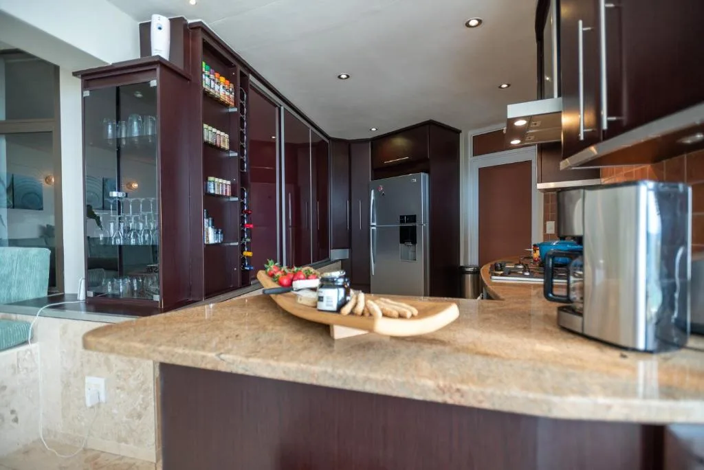 Modern kitchen with dark cabinetry, stainless steel appliances, and stone countertop