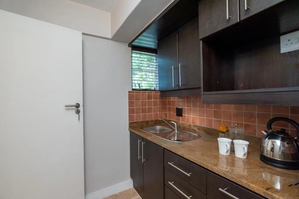 Modern kitchen with dark cabinetry, terracotta tile backsplash, and granite countertop
