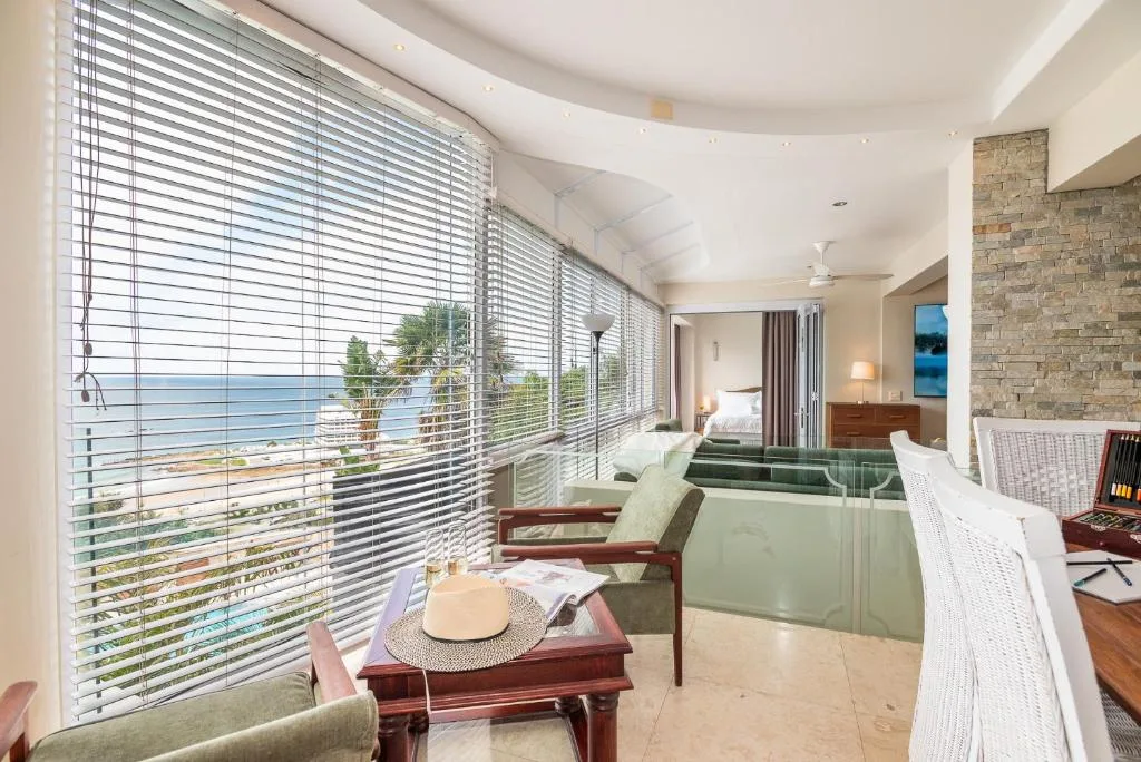 Spacious lounge with ocean views through horizontal blinds and comfortable seating