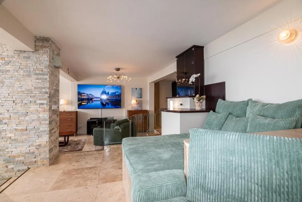 Modern lounge with sage green sofa, wall-mounted TV, and ambient lighting