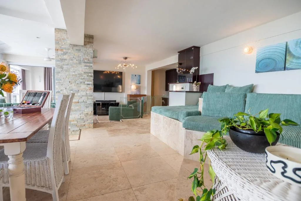 Open-plan lounge with green sofa, TV, and dining area beyond