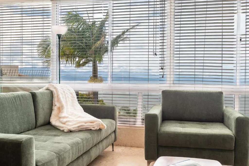 Modern living room with gray sofas overlooking ocean views through slatted blinds