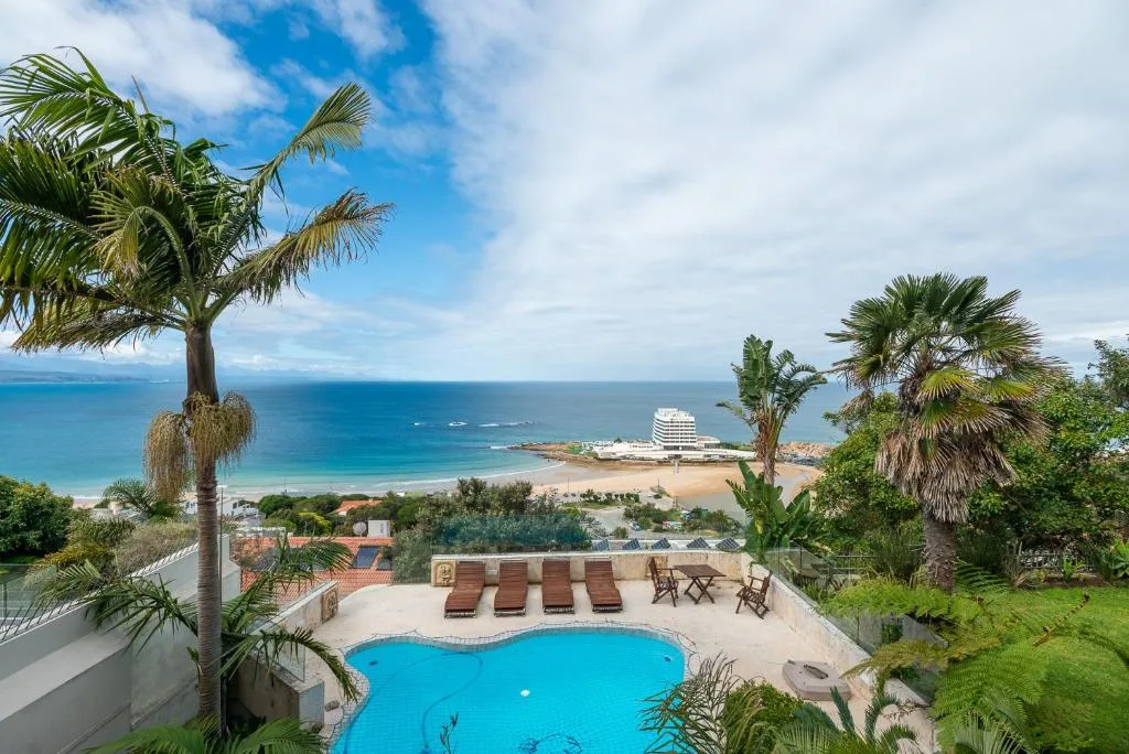 Swimming pool with ocean and beach view in background