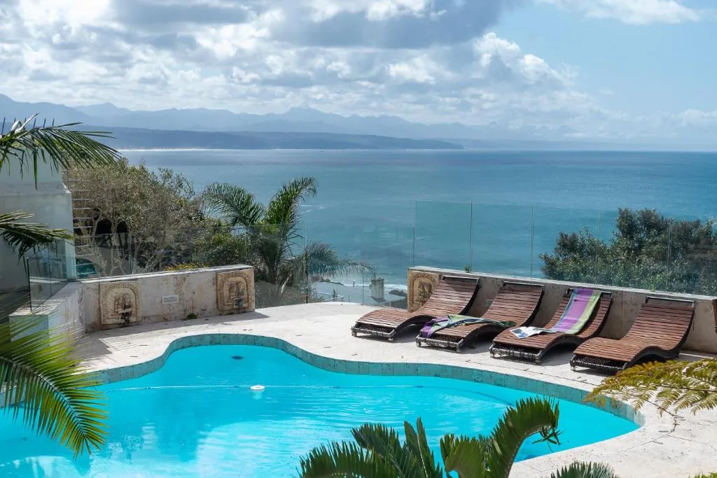 Turquoise swimming pool with ocean and mountain views beyond